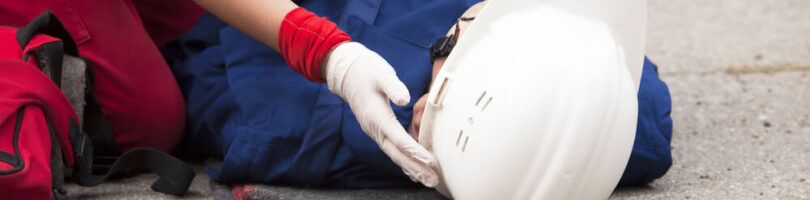 worker in white hardhat laying concrete with another worker checking to see if they are injured - workers compensation lawyer