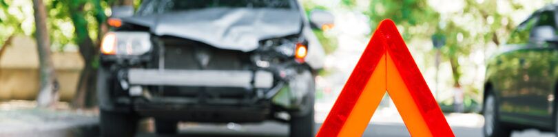road hazard sign in front of car with damage to hood