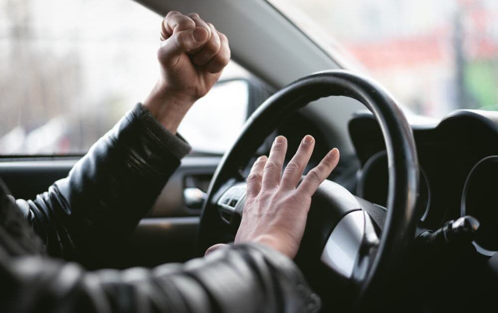 driver honking car horn with raised fist in the air