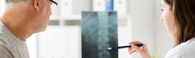 doctor showing patient x-ray image of spinal cord injuries